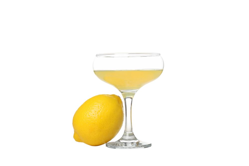 Whole lemon and cocktail glass with limoncello, isolated on light background