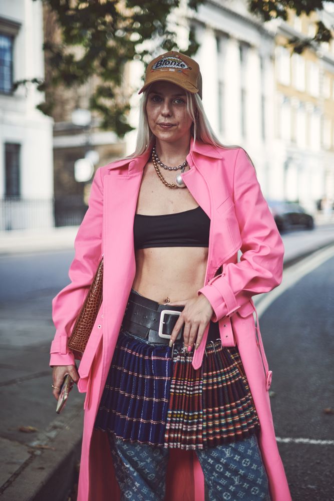 London, England, United Kingdom - September 18 2021: Blonde woman in cap and pink trench coat