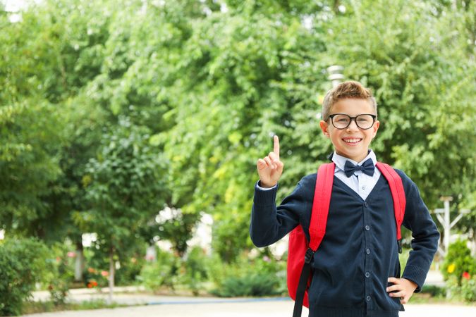 Boy in school uniform against greenery background, space for text