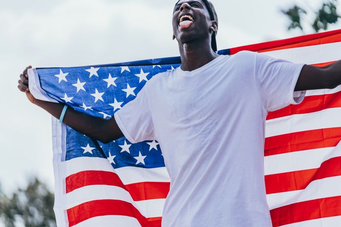 Black man wrapped in American Flag outside