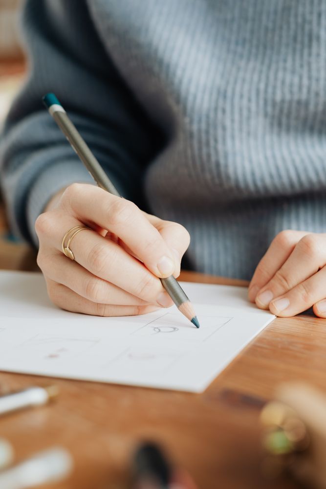 Cropped image of person in blue sweater drawing on paper