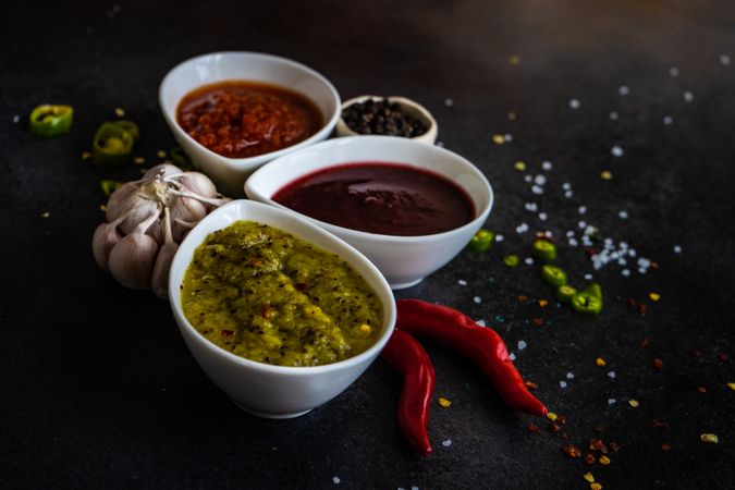 Three flavorful spicy traditional Georgian sauces on dark counter with copy space