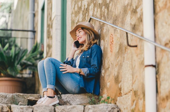 Woman with smartphone sitting on stone steps of stairs