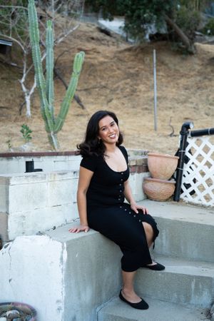 Woman with beautiful smile sitting on steps in her yard looking at camera