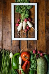 Composition with vegetables and white frame in wooden table