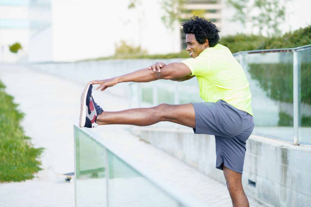 Man stretching his leg on outdoor railing