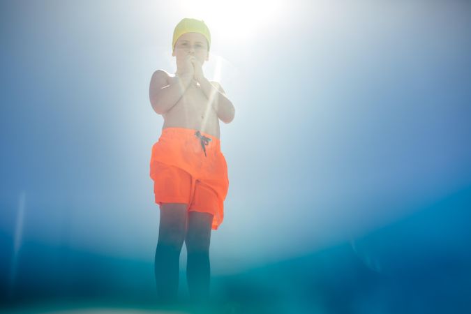 Boy wearing swimming shorts and photographed from underwater