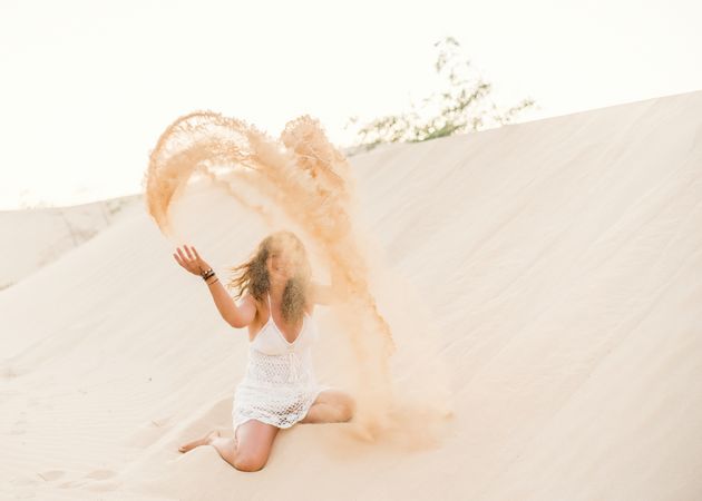 Woman having fun throwing sand in desert