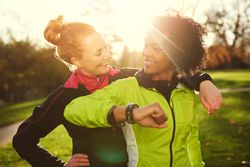 Two woman smiling at each other in a sunny park