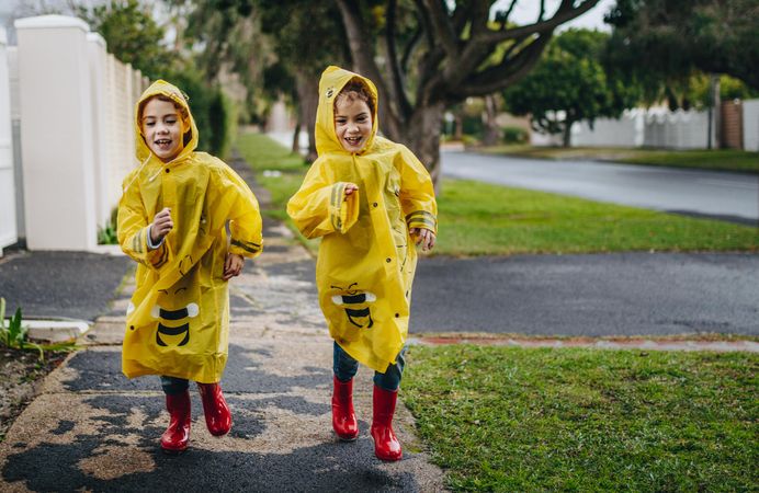 Little girls running outdoors in rainy weather