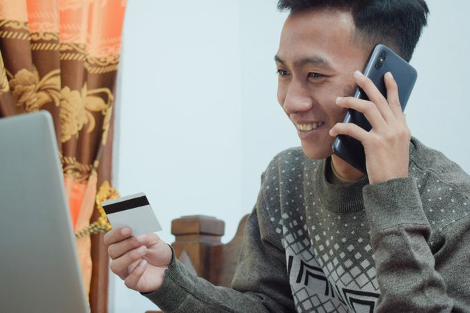 Young man shopping online holding credit card and smartphone