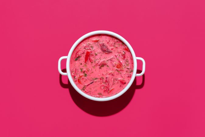 Beetroot soup with sour cream in a bowl, isolated on magenta background