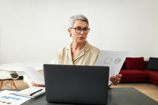 Woman with short grey hair looking at pie charts in her home office