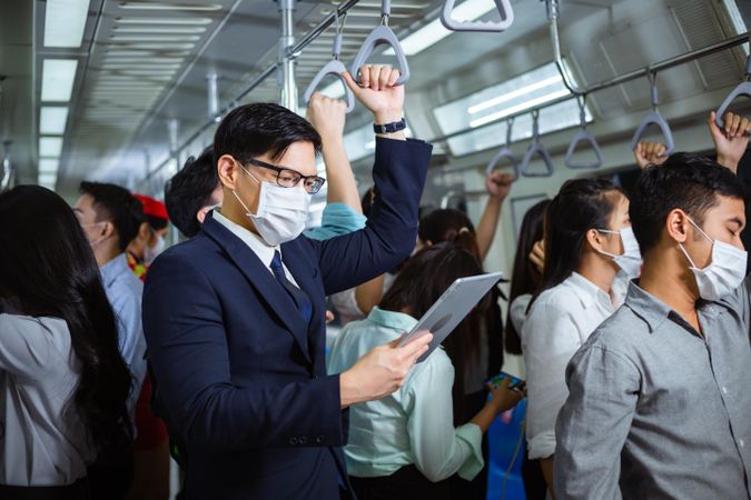 Businessman standing reading tablet in busy metro car