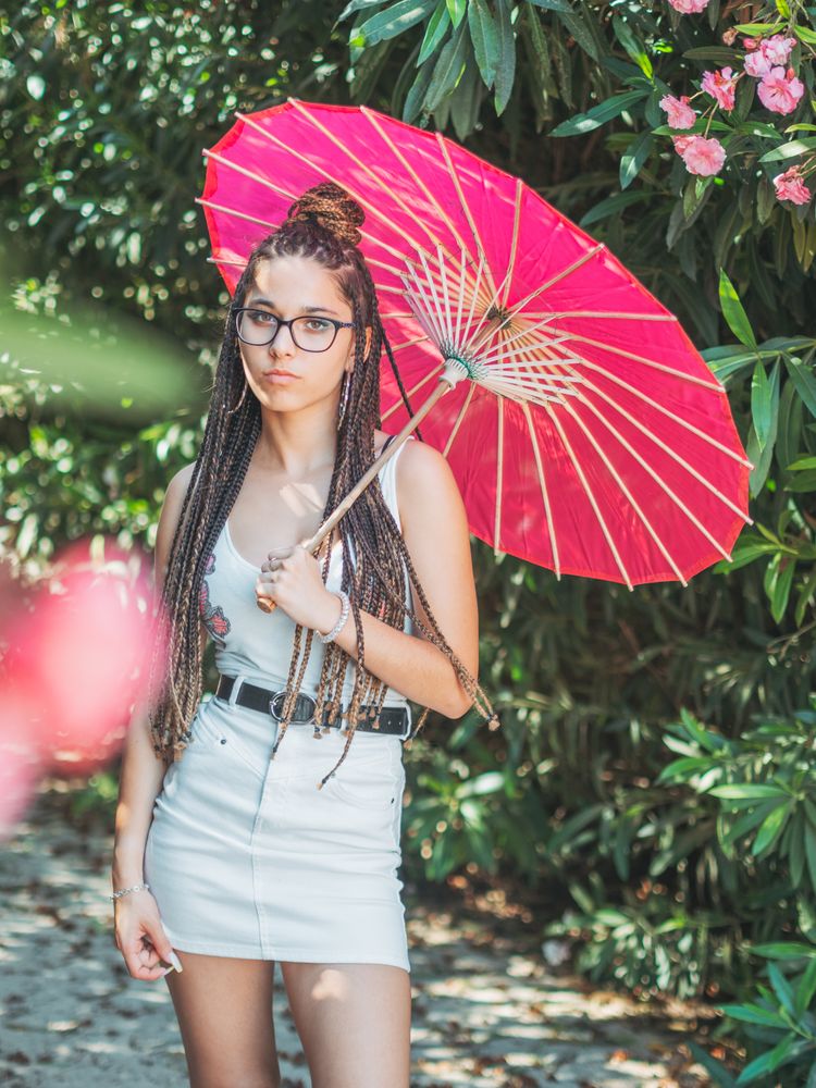 Fit young female with umbrella standing near blooming trees