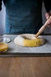Crop cook smearing Rosca de Reyes with egg