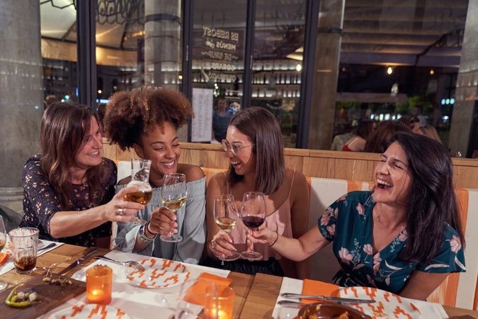 Diverse positive friends clinking wineglasses