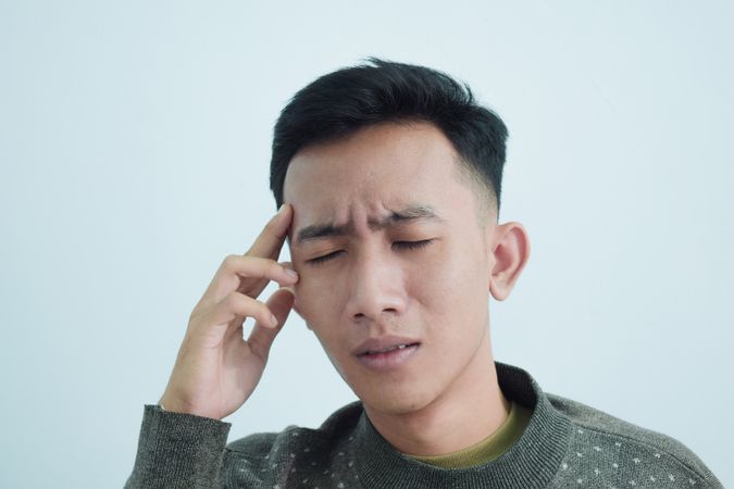 Asian young man touching temples with headache