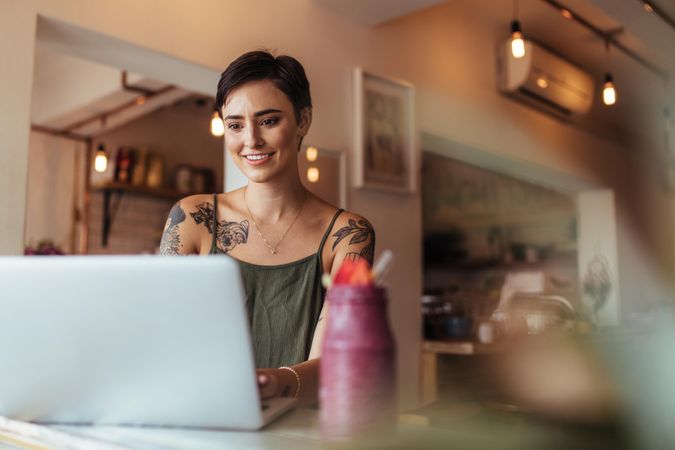 Woman with tattoos on her body working on laptop