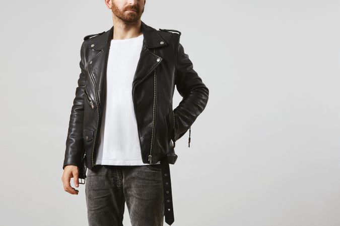 Man in dark leather biker jacket and light t-shirt with hand in pocket