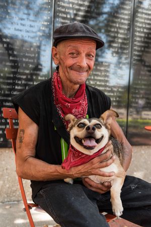 Man smiling, with dog in matching red bandanas, Dallas, Texas