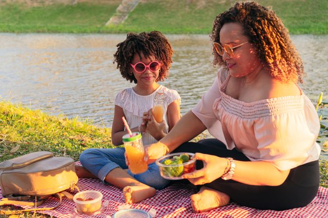 Mother and daughter eating vegan food during summer vacation outdoor trip