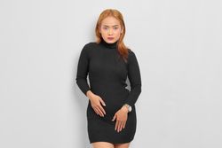 Asian woman looking at camera with red hair and turtle neck dress in studio