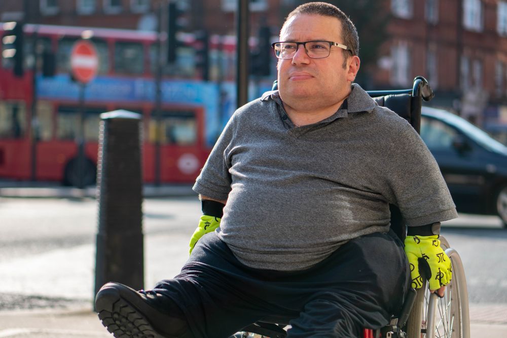 Portrait of man in wheelchair going through city sidewalk