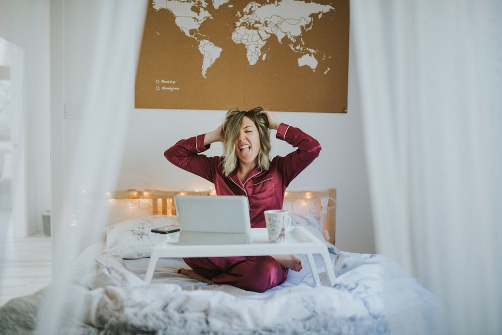 Woman stretching in bed with laptop