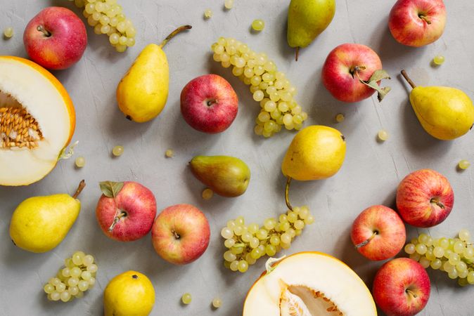 Scattered grapes, melon, apples and pears on grey table