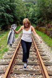 Woman walking along railway though greenery part of road