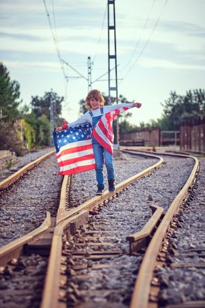 Kid smiling with USA national flag on rails
