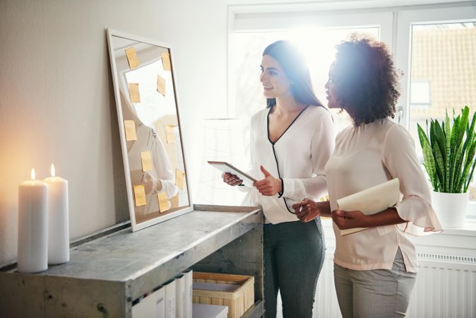 Two colleagues brainstorming with sticky notes on a board