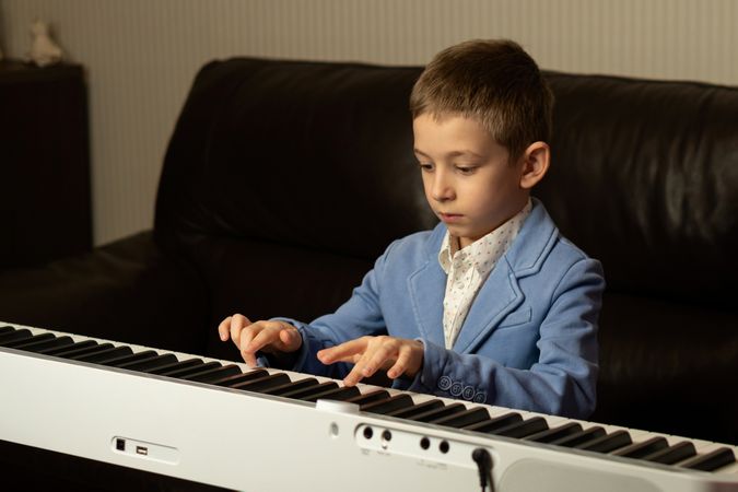 Serious young boy playing a digital piano.