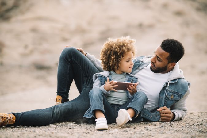 Black father relaxing in nature with ethnic kid