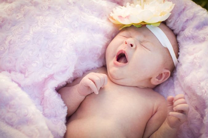 Yawning Newborn Baby Girl Laying in Soft Blanket