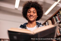 Young biracial student smiling and reading textbook 4MzAyb