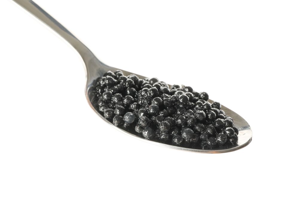 Spoon with caviar isolated on plain background