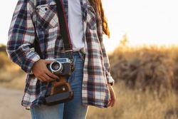 Unrecognizable woman taking photos with analog camera at sunset