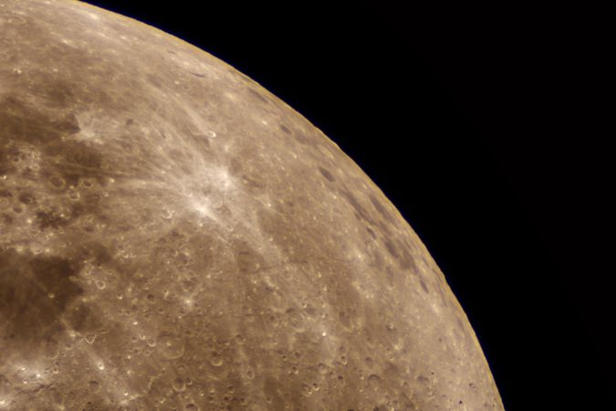 Partial lunar sphere revealing bright radial marks on cratered surface