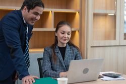 Male and female colleagues smiling over a laptop