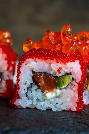 Close up of Japanese sushi rolls with roe, avocado and salmon with copy space