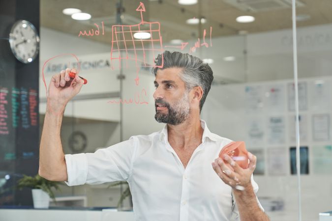 Concentrated engineer with model of respirator taking notes