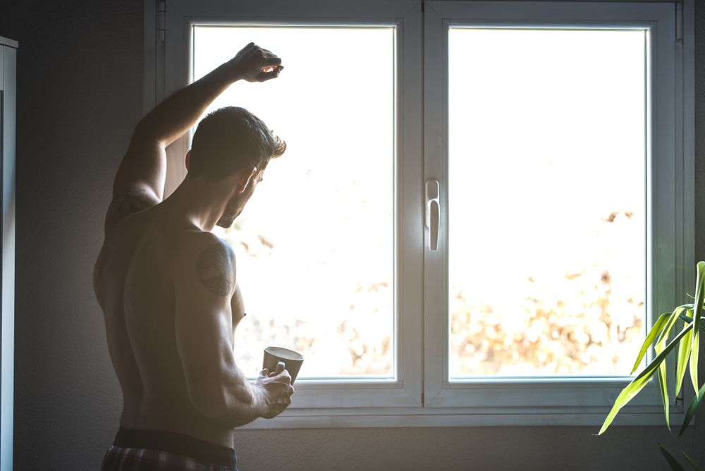 Man standing by a windows with a cup of coffee