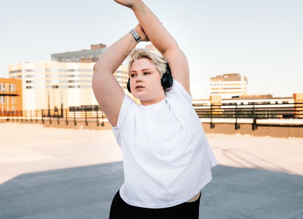 Curvy woman stretching her arms on a rooftop