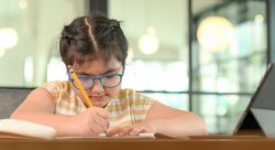Cropped shot of Asian girl with glasses studying at home