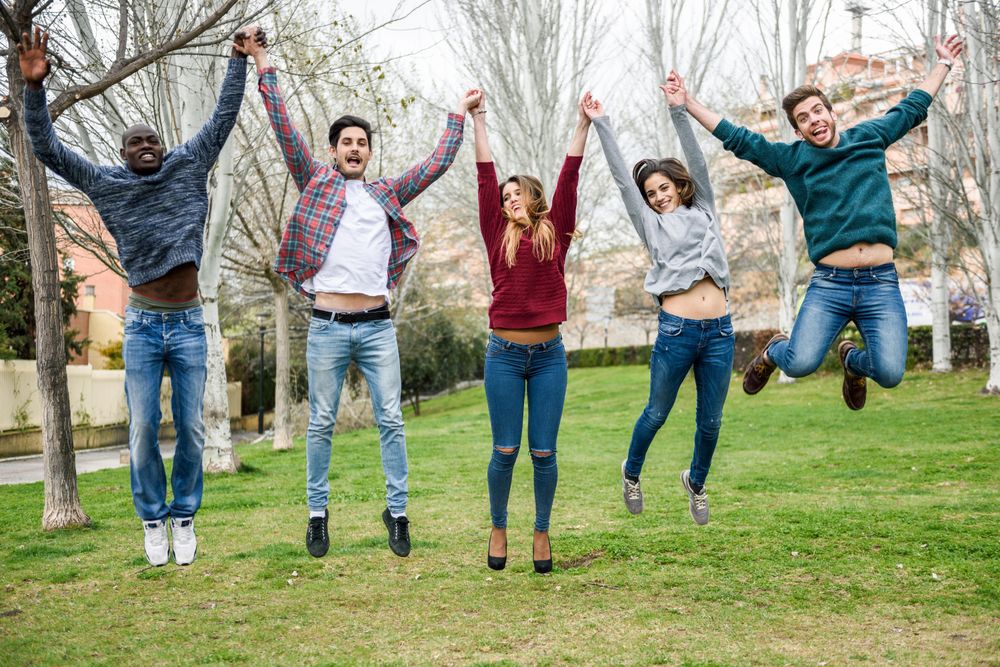 Joyful friends jumping together in park