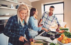Woman slicing lemons as her friends cook asparagus next to her