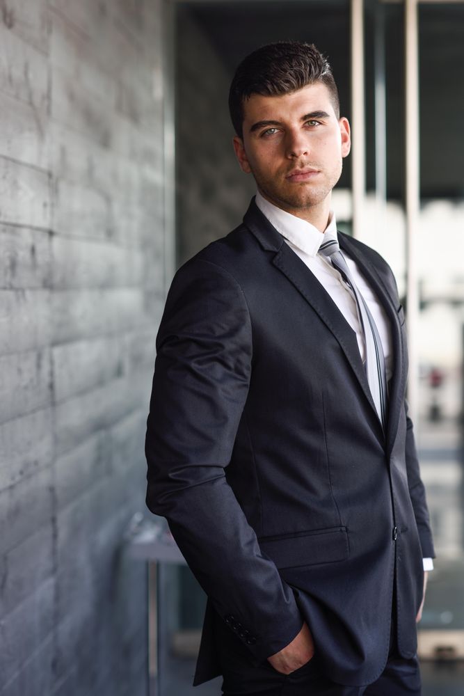 Portrait of man with blue eyes in suit and tie with hands in pockets
