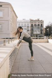Side view of young woman stretching on a rooftop in the city beXpp4